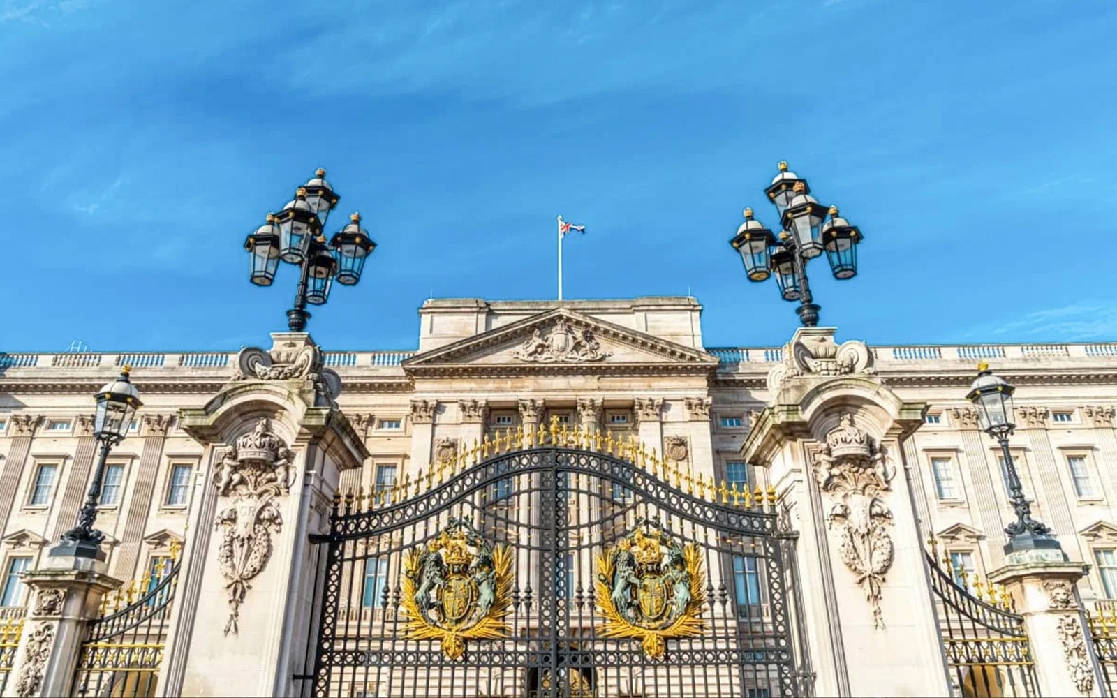 Buckingham Palace gates and facade under a clear blue sky, London.
