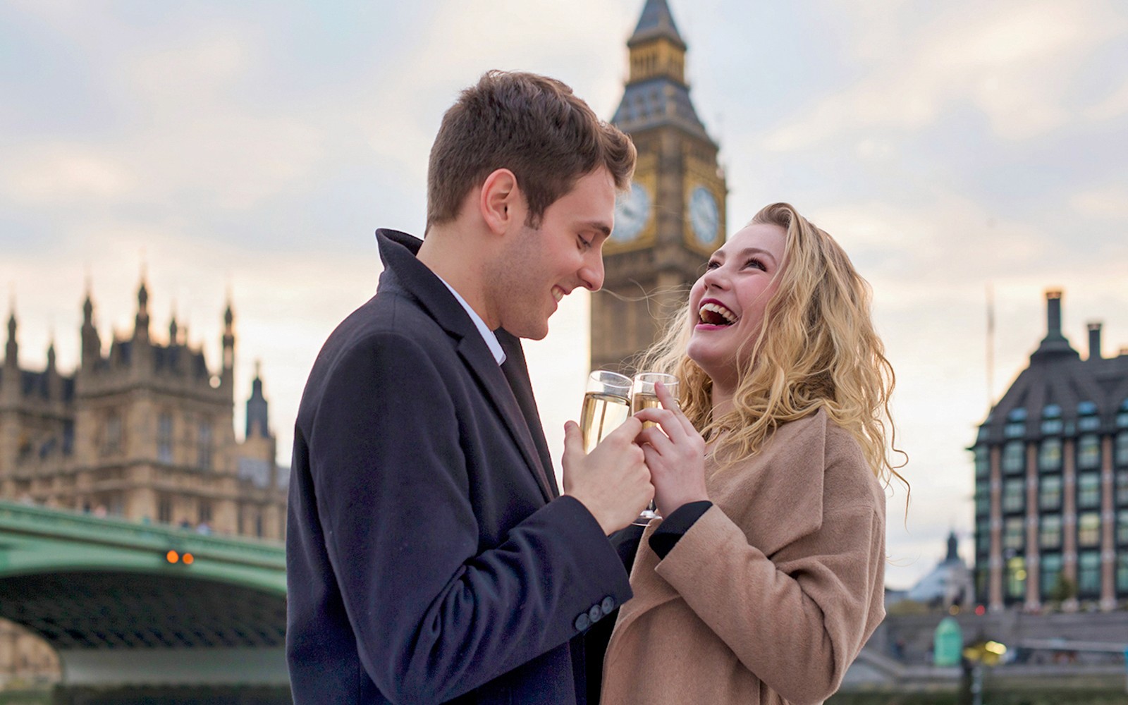 Couple enjoying sparkling wine on Thames River cruise with Big Ben in the background.