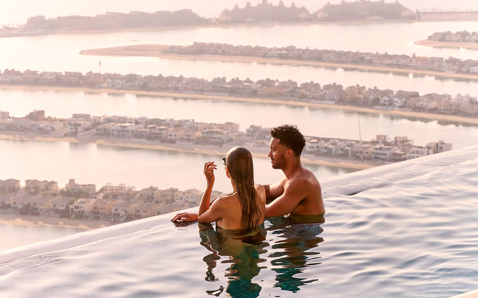 A couple experience sunrise at the edge of the AURA infinity pool looking out over the Palm.