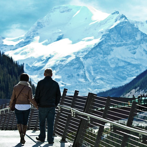 A couple walk along the scenic skywalk overlooking the mountains.