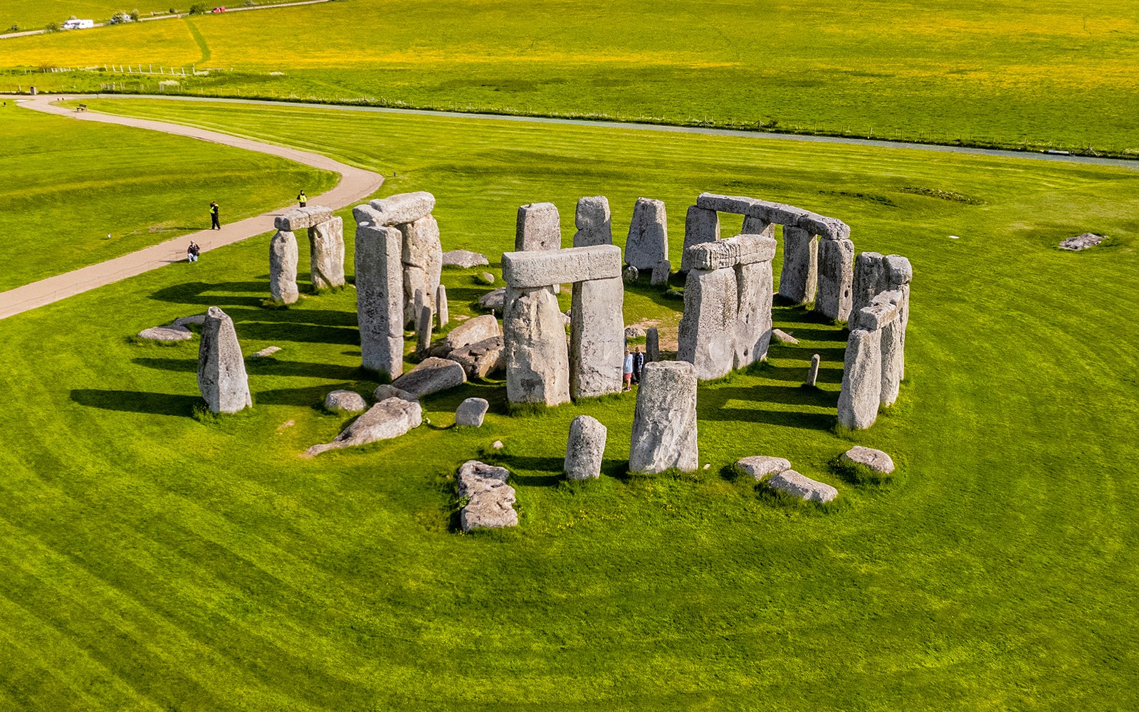 Tourists walking around Stonehenge on a day trip from London.