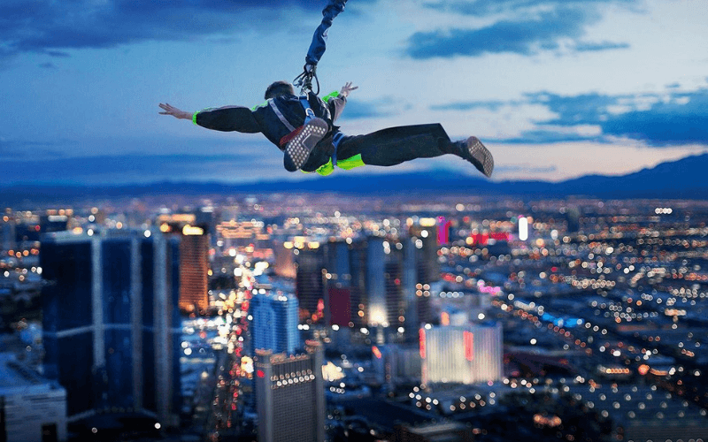 Ein SkyJump-Teilnehmer hängt in der Luft, Arme und Beine ausgestreckt, mit den Lichtern des Vegas Strip unter ihm.